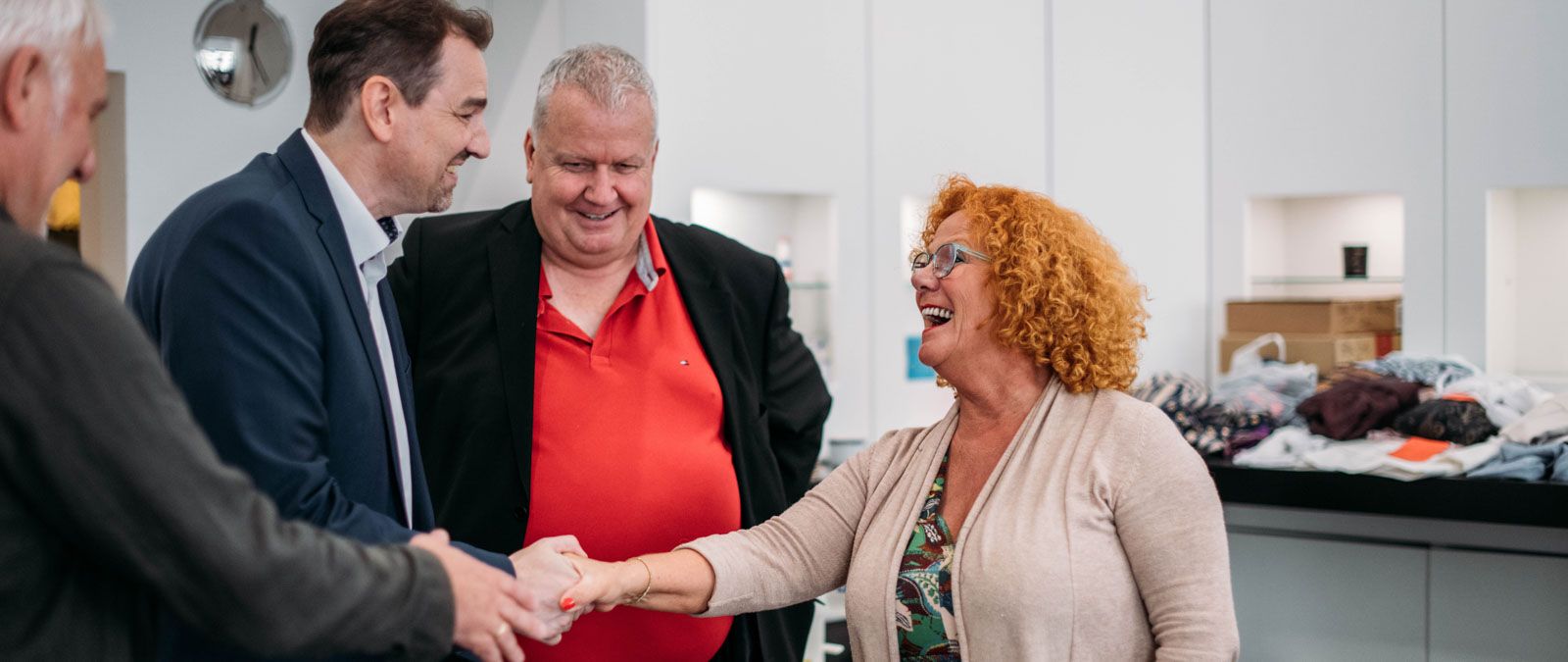 Vier Personen begrüßen sich in einem Büro.